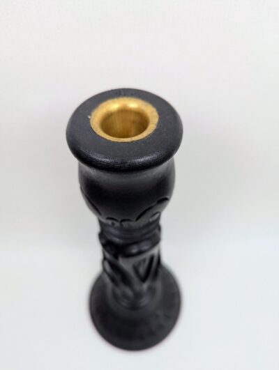 Vue de dessus d'un bougeoir en bois sculpté noir avec insert central en laiton doré