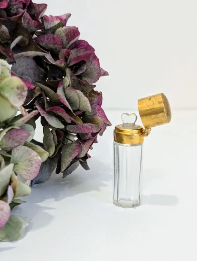 Petit flacon de parfum de poche XIXe siècle en verre transparent et armature en métal doré ciselé, bouchon en forme de cœur, objet de collection romantique.