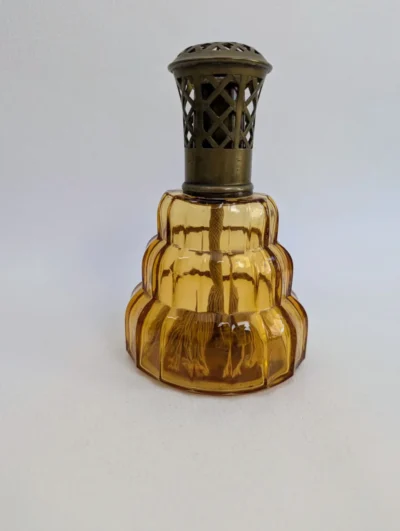 Lampe Berger vintage en verre couleur ambre avec monture ajourée en bronze ou laiton vieilli, modèle classique de collection.
