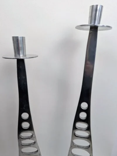 Paire de grands bougeoirs élancés en métal argenté de style brutaliste avec base évidée et design géométrique industriel.