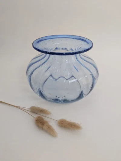 Vase boule en verre soufflé artisanal bleu cobalt avec col évasé et bouquet d'hortensias séchés sur fond texturé