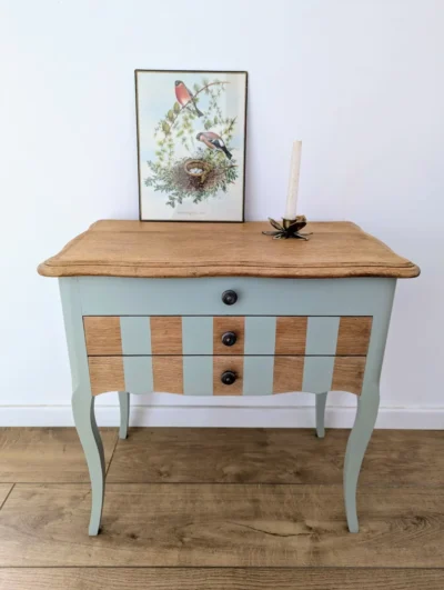 Petit meuble vintage rénové vert sauge avec coffre et deux tiroirs, décor rayures graphiques et pieds compas, 60x36 cm.