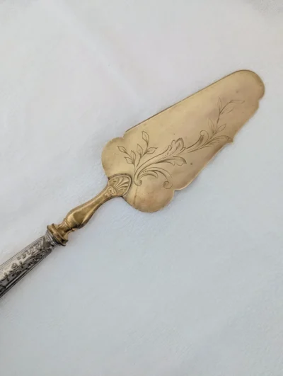 Pelle à tarte vintage bicolore avec palette dorée et manche en métal argenté ciselé, décor floral artisanal pour service à dessert élégant.
