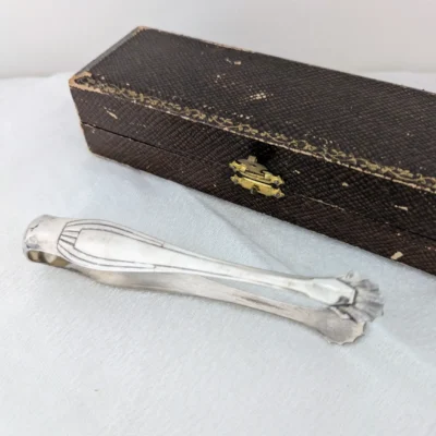 Pince à sucre Art Déco en métal argenté dans écrin bijouterie Raoul Simon - Villa Brieg