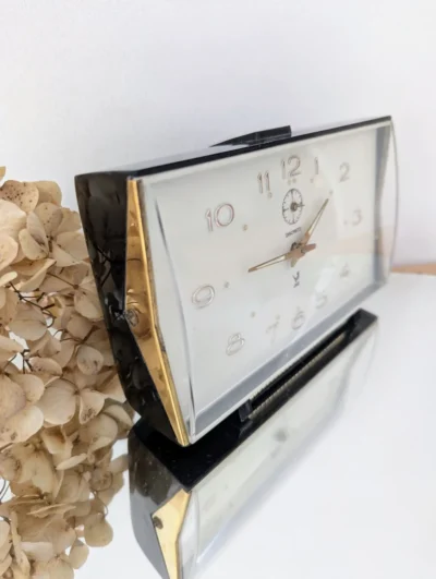 Réveil JAZ Discreto mécanique vintage des années 60, cadre en laiton doré avec verre bombé et socle en bakélite noire, horlogerie française de collection.