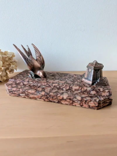 Encrier ancien de style Art déco avec socle en marbre rose veiné et figurine d'oiseau stylisée en cuivre massif, accessoire de bureau vintage de collection.