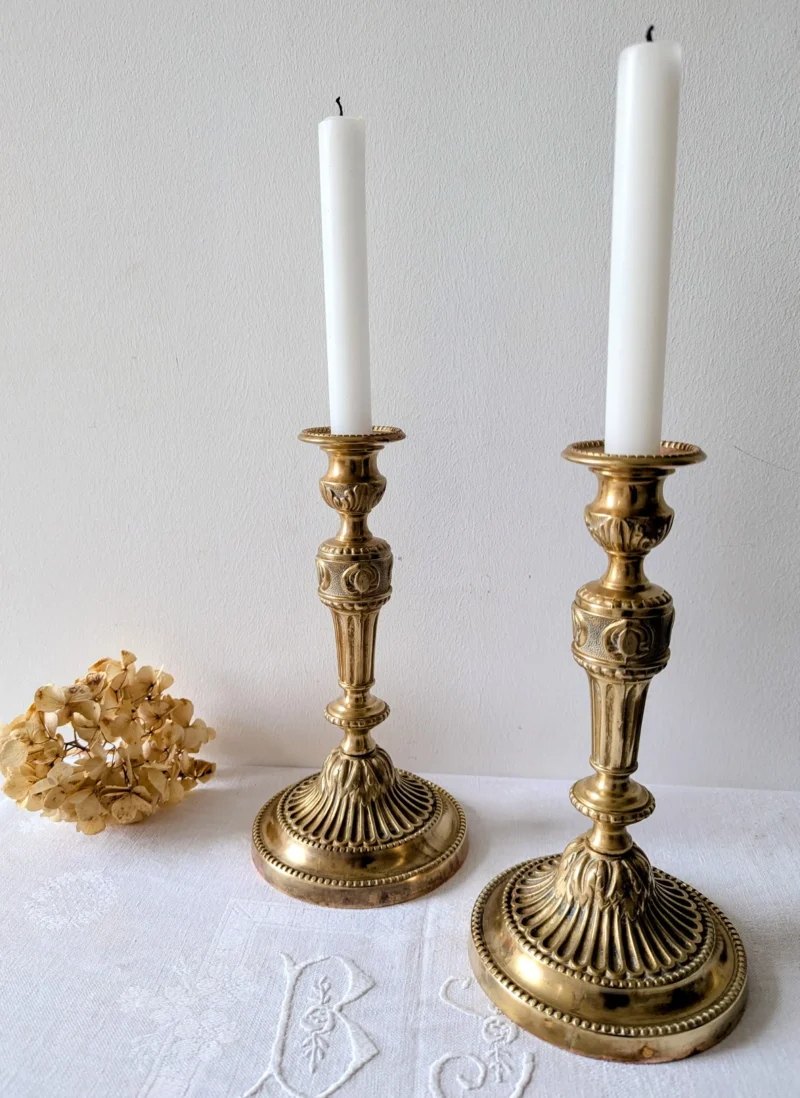 Bougeoirs vintage en laiton posés sur une console en bois, décoration murale chaleureuse Villa Brieg