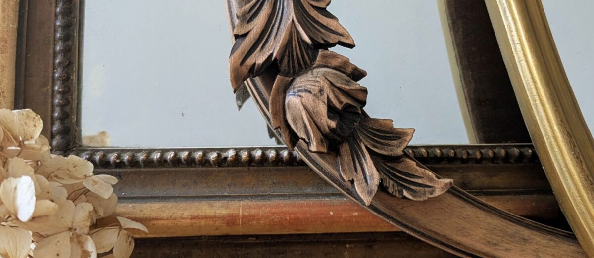 Détail d'un miroir ancien doré et cadres patinés Villa Brieg : moulures sculptées et perles pour une décoration murale de caractère.