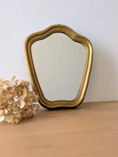 Petit miroir doré vintage galbé en bois massif, cadre doré à la feuille d'or des années 50, décoration murale ancienne.