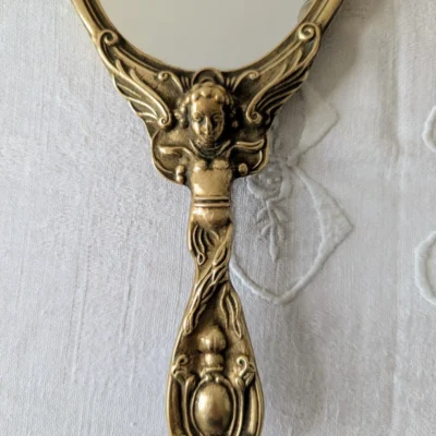 Poignée sculptée d’angelot sur miroir ancien