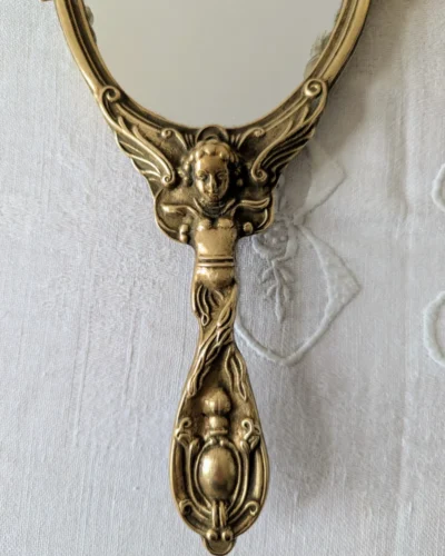 Poignée sculptée d’angelot sur miroir ancien