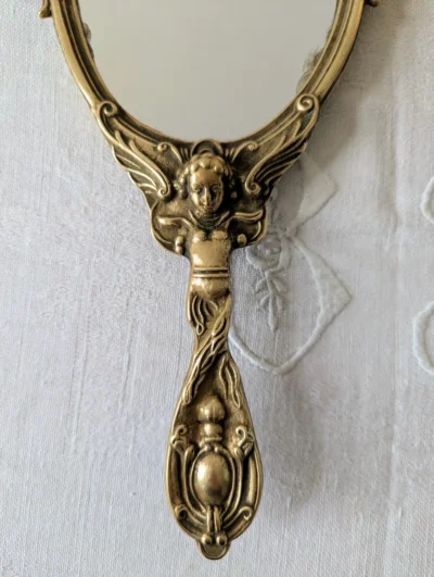 Poignée sculptée d’angelot sur miroir ancien