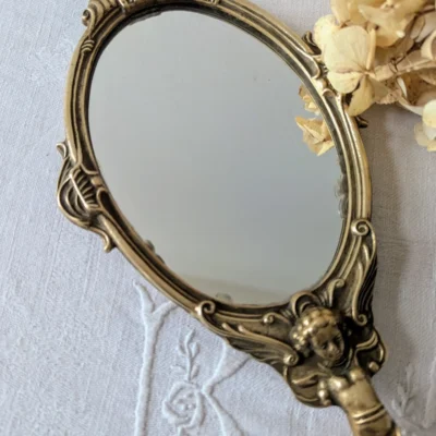 Miroir à main ancien en bronze patiné décoré d’angelots
