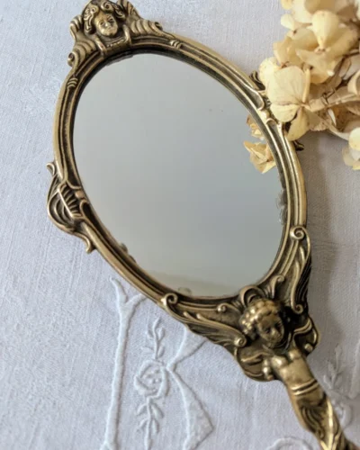 Miroir à main ancien en bronze patiné décoré d’angelots