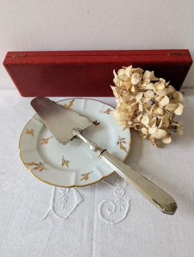 Pelle à tarte vintage en métal blanc avec manche ciselé et son écrin d'origine rouge et satin blanc, ustensile de service milieu du XXe siècle.