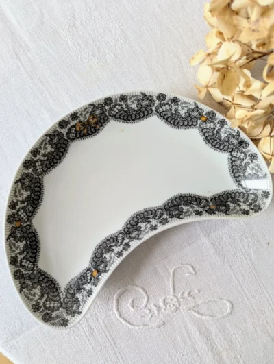 Plat en porcelaine de Limoges Georges Boyer pour Marcel Rochas, décor dentelle noire et nœuds dorés, forme demi-lune vintage.