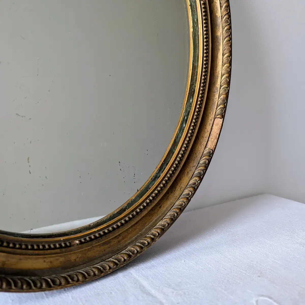 Gros plan sur la dorure ancienne patinée et les moulures du bois