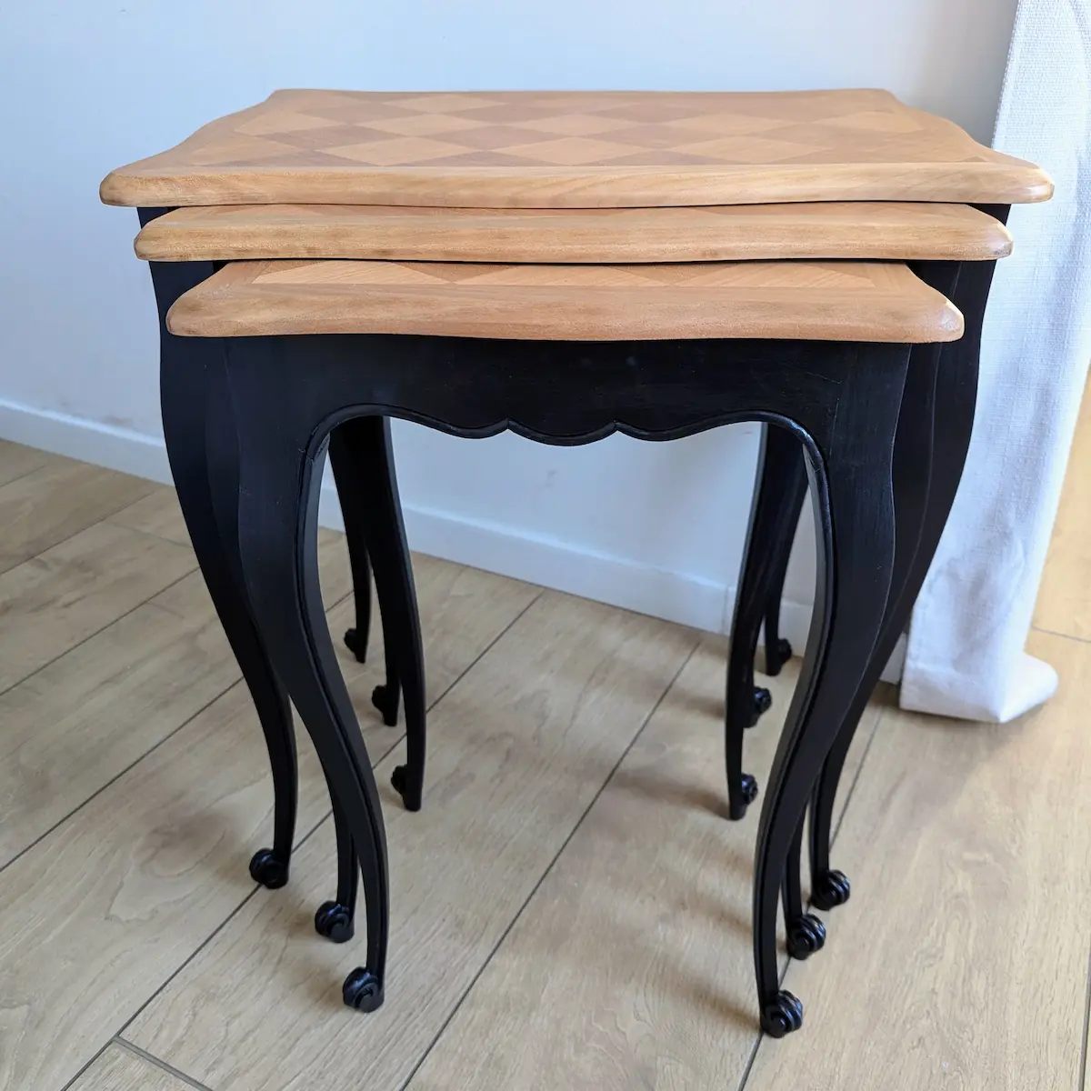 Vue de profil des tables gigognes anciennes montrant l'emboîtement des pieds noirs