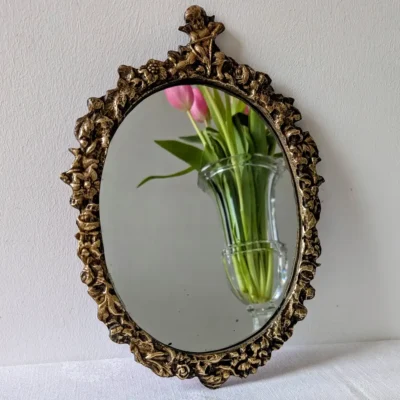 Reflet de tulipes roses dans un miroir ancien vintage doré posé sur une table.