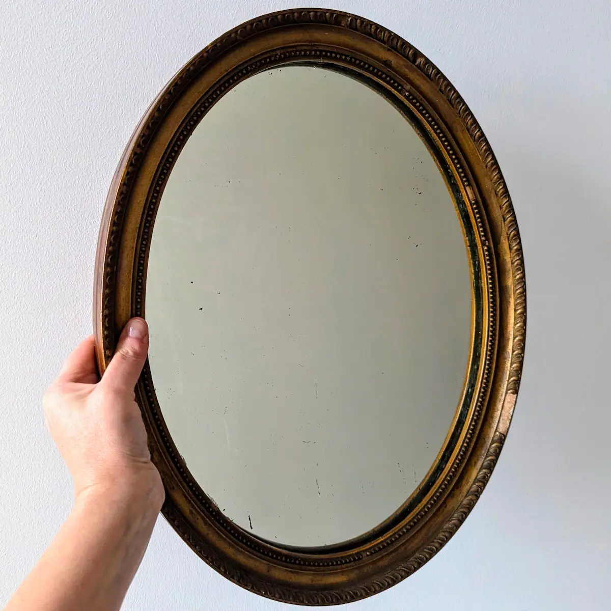 Main tenant le miroir ancien ovale pour montrer l'échelle