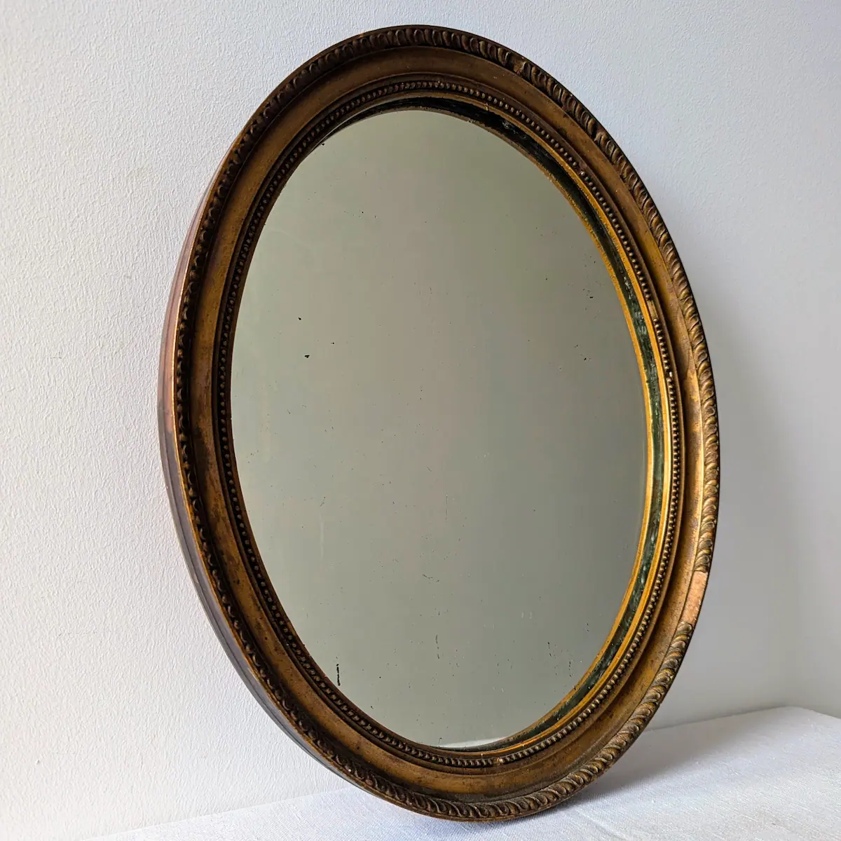 Vue de trois-quarts d'un miroir vintage ovale doré