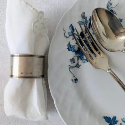 Mise en scène d'une table avec rond de serviette Christofle et couverts anciens.