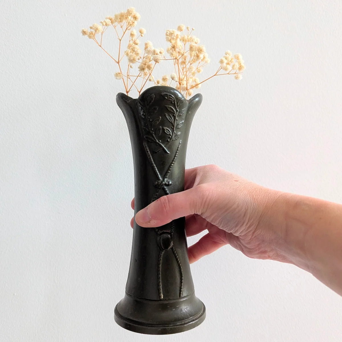 Vase ancien en régule tenu à la main pour échelle