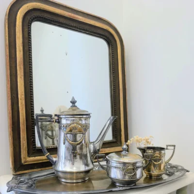 Service à café ancien posé devant un miroir ancien doré.