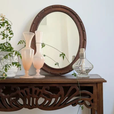 Miroir ancien posé sur une console avec vases décoratifs