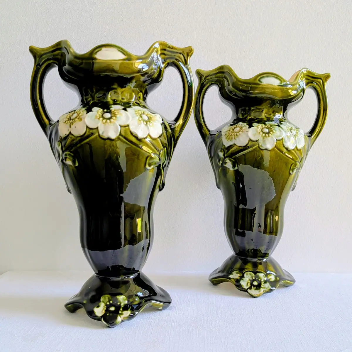 Paire de vases anciens en barbotine verte au décor floral en relief