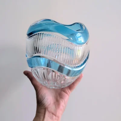 Main tenant le vase en cristal bleu pour montrer sa taille et sa densité