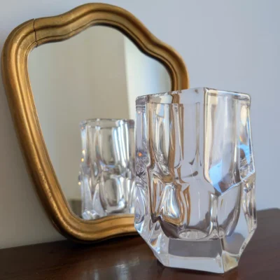 Vase en cristal de Sèvres vintage devant un miroir doré.