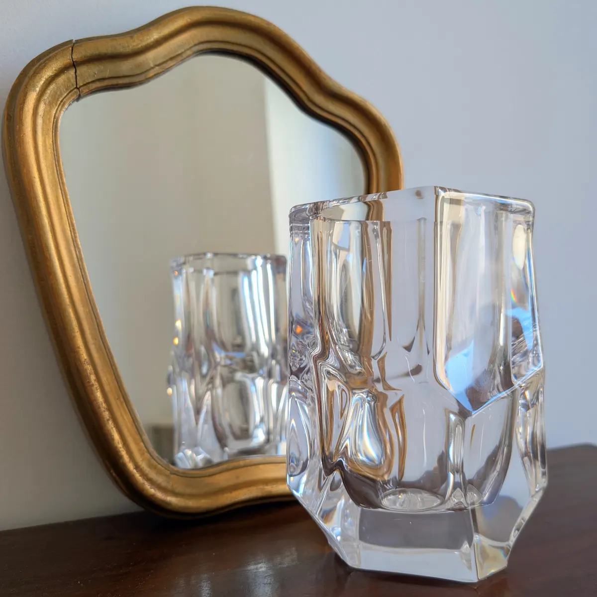 Vase en cristal de Sèvres vintage devant un miroir doré.