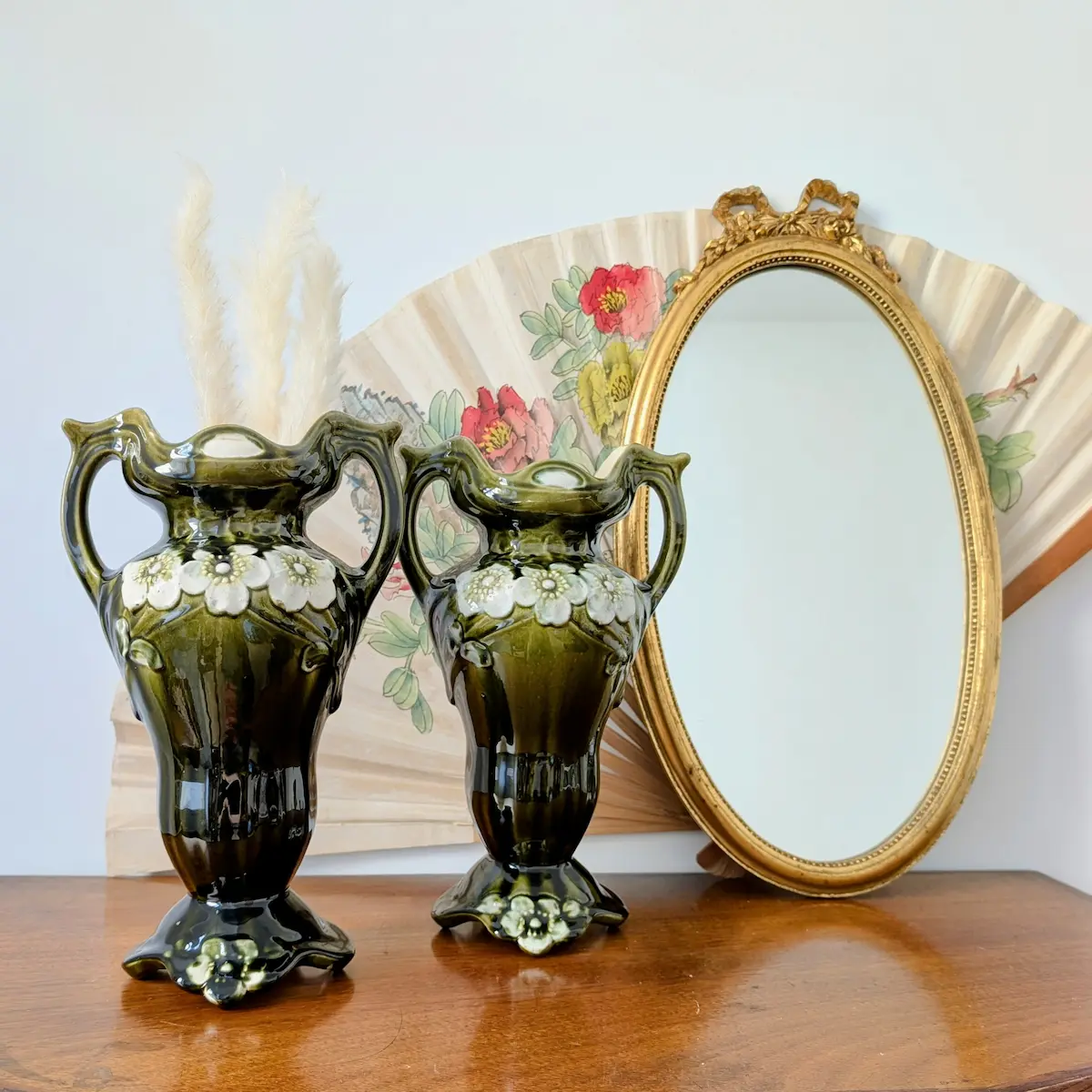 Vases en barbotine verte devant un miroir ancien sur une cheminée