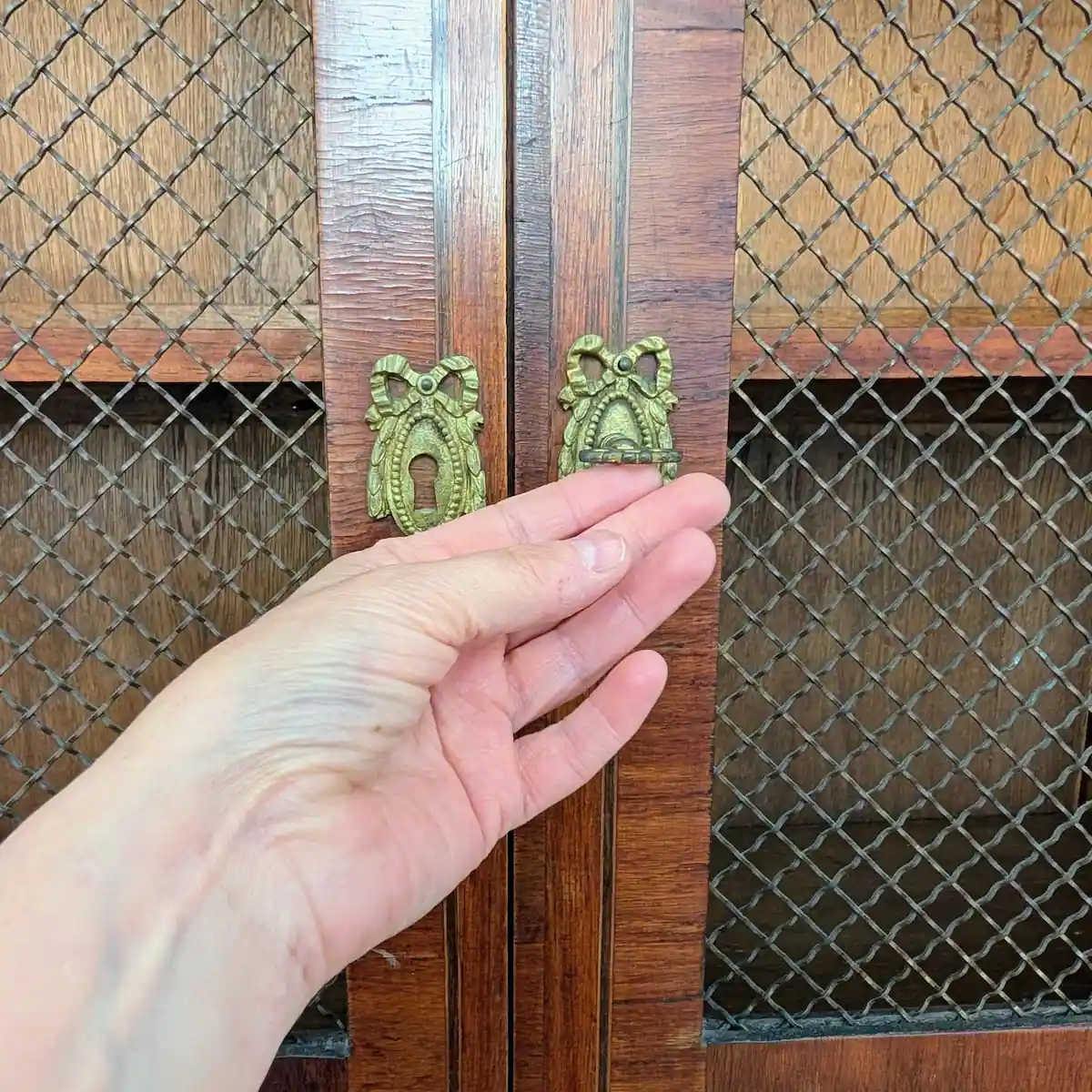 Main ouvrant la serrure d'une bibliothèque ancienne avec sa clé d'origine en bronze