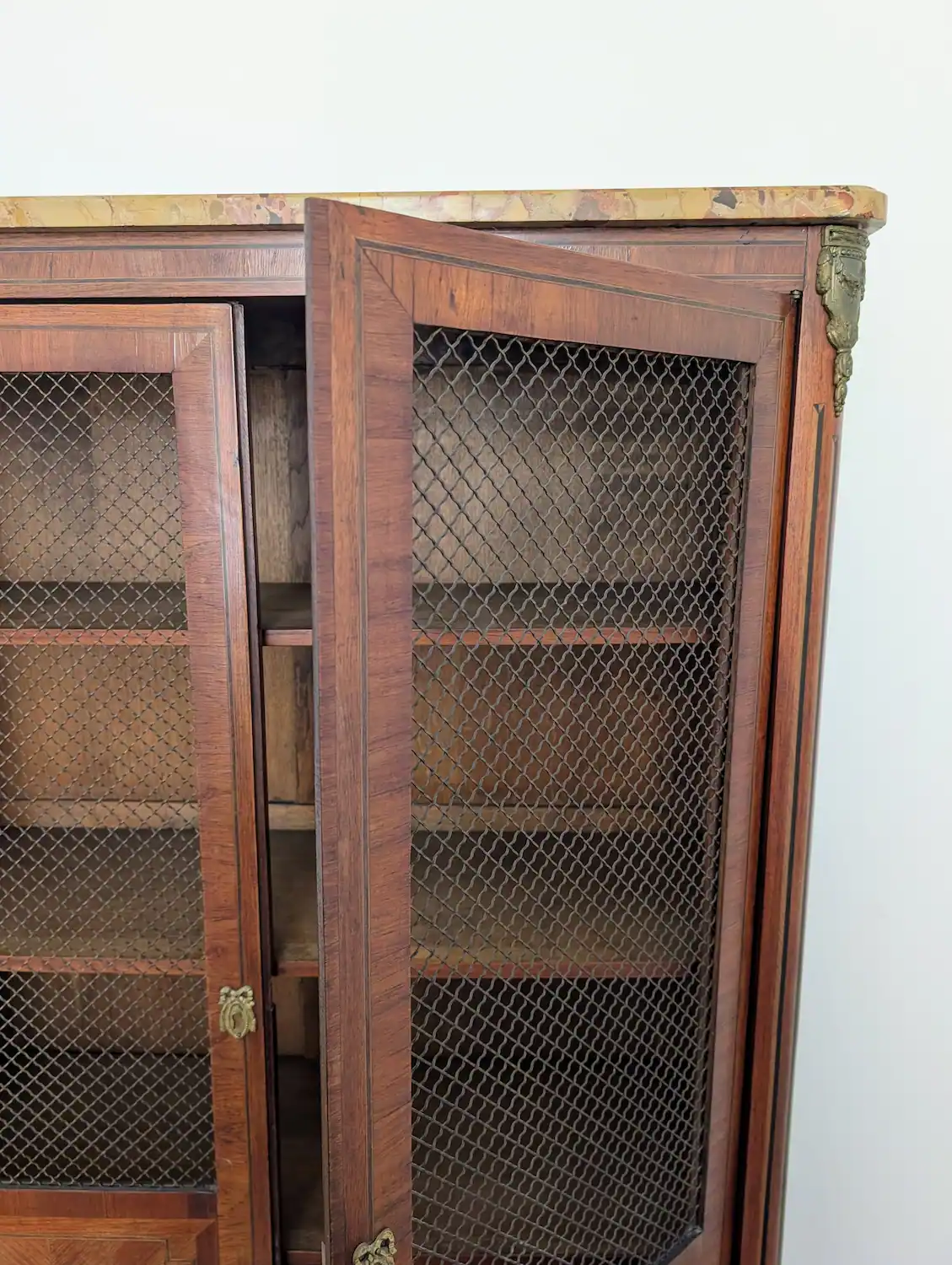 Zoom sur la porte grillagée et le placage en chevrons style Louis XV