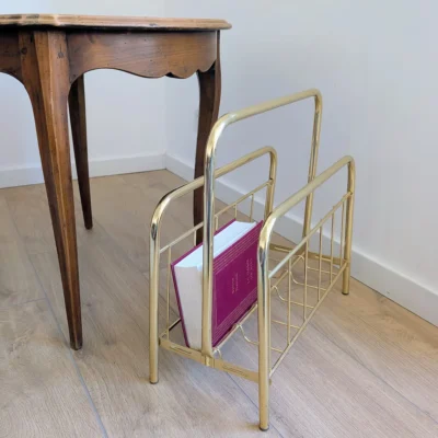 Porte-revues vintage doré en situation près d'une table ancienne