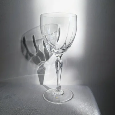 Un jeu de lumière et d'ombre projeté à travers la taille d'un verre en cristal ancien.