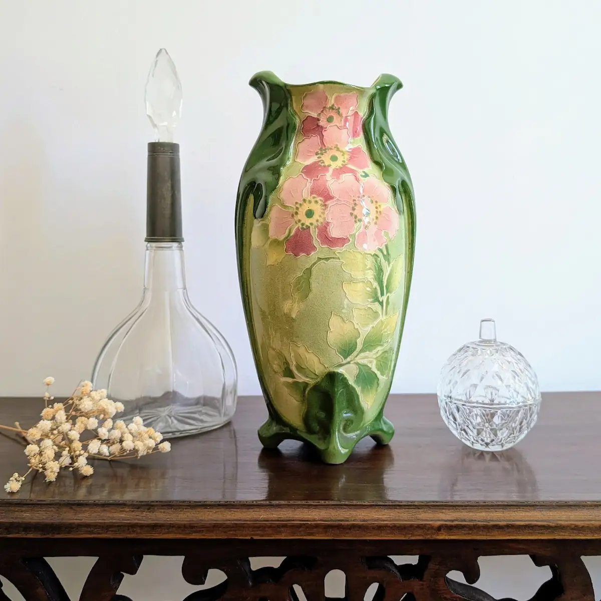 Vase ancien Art Nouveau en céramique verte mis en scène sur une console en bois