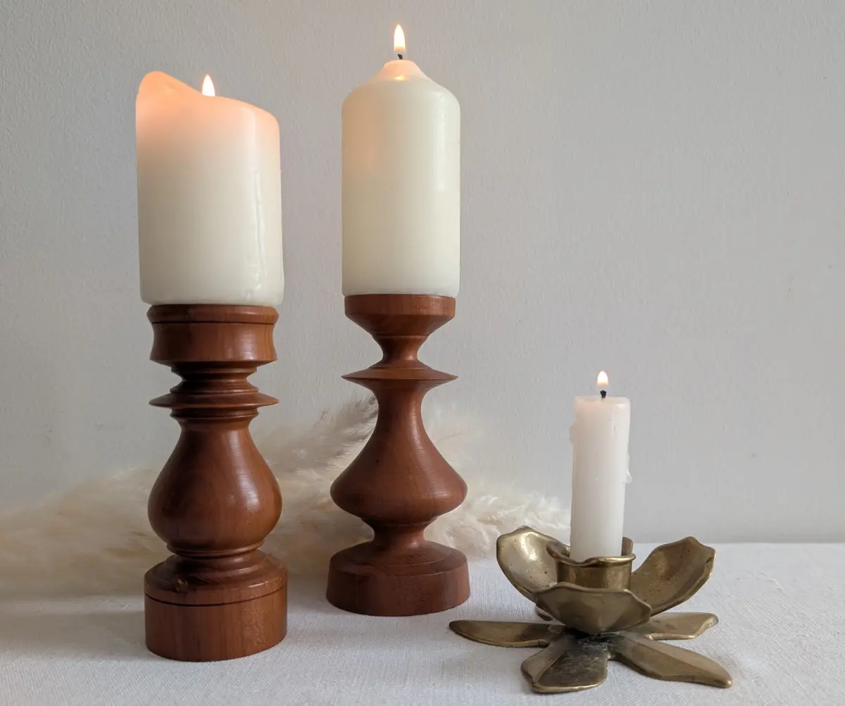 Trio de bougeoirs anciens en bois tourné et détails de laiton avec une bougie beige allumée