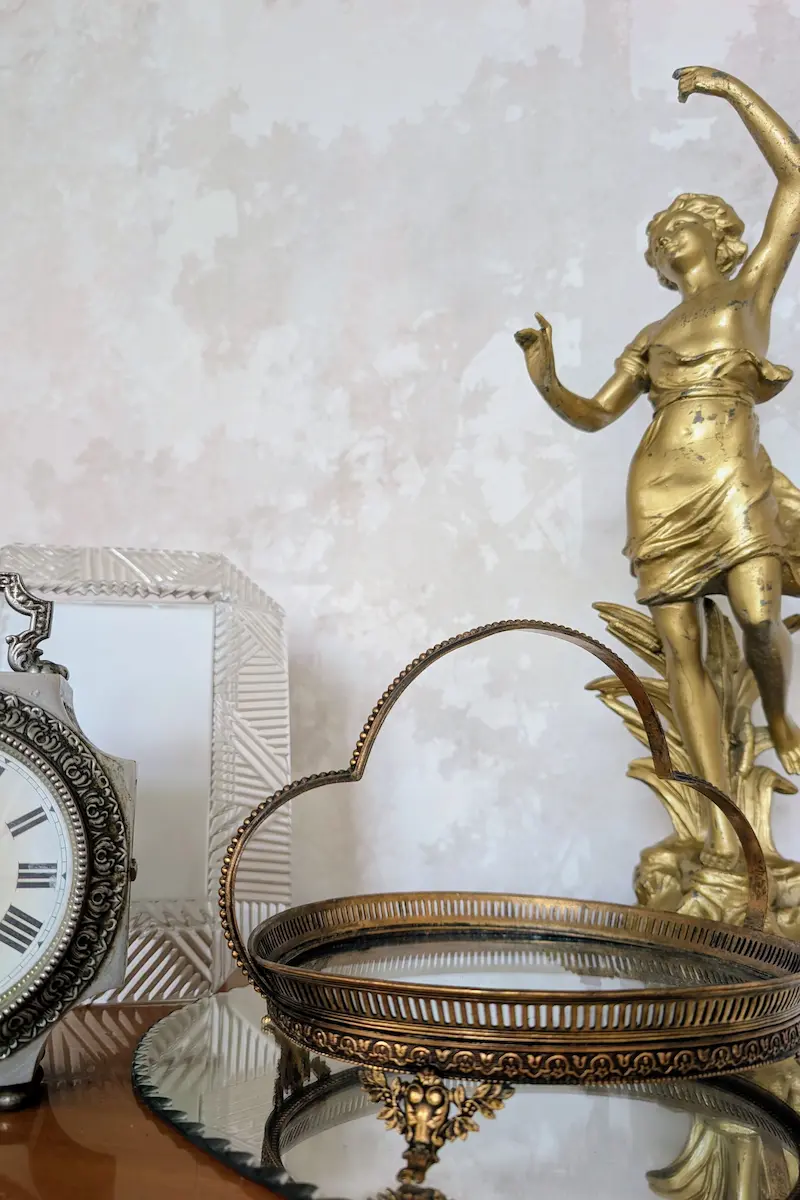 Statuette dorée et horloge ancienne argentée illustrant les codes de la décoration vintage authentique.