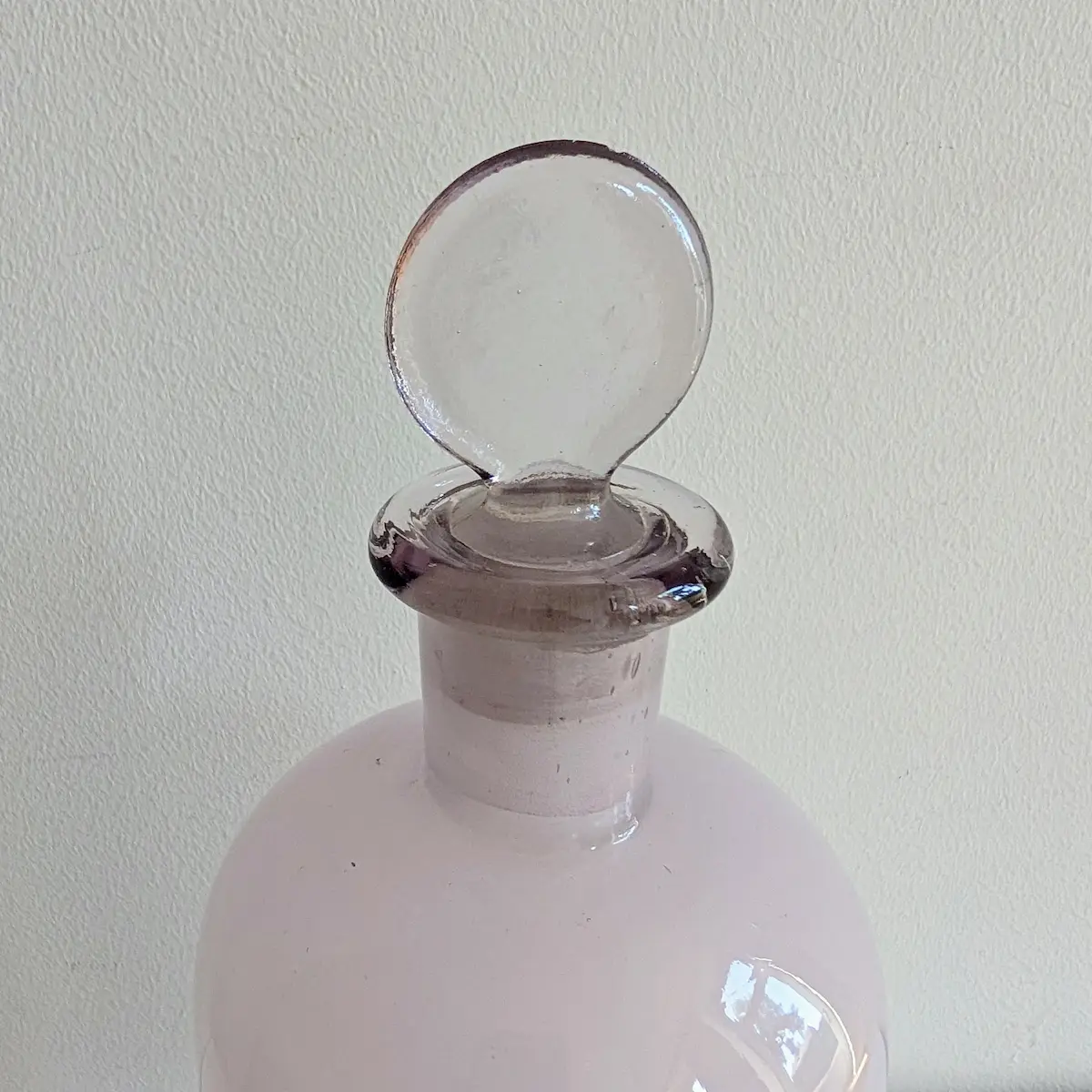 Gros plan sur le bouchon boule en verre plein inséré dans le col rodé du flacon.