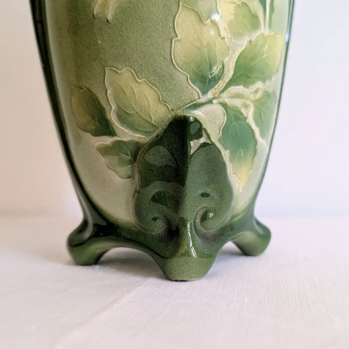 Gros plan sur les pieds nervurés et les motifs de roses en relief du vase ancien