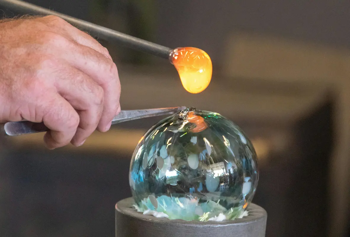Gros plan sur le façonnage à la pince d'un vase en verre soufflé artisanal