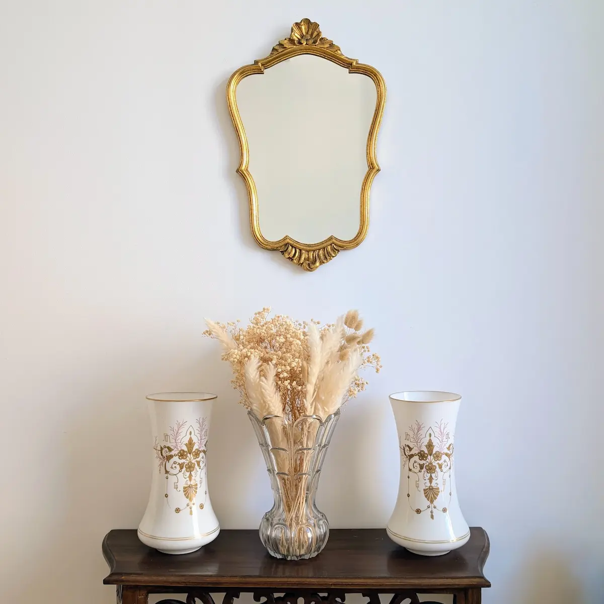 Miroir chantourne dore style rocaille suspendu dans une entree au-dessus d une console en bois