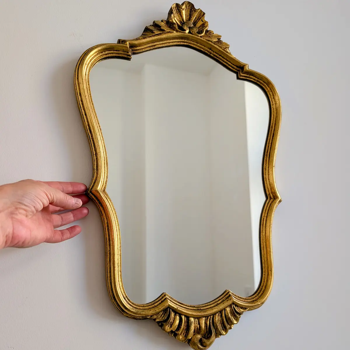 Miroir chantourne dore 53 cm tenu a la main