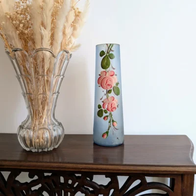 Vase ancien bleu posé sur une console en bois sculpté à côté d'un vase en cristal