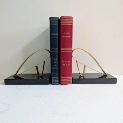 Serre-livres vintage laiton et marbre noir encadrant des livres anciens