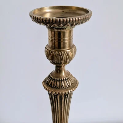 Détail du binet ciselé de perles et de feuilles d'eau sur un bougeoir en laiton de style Louis XVI.
