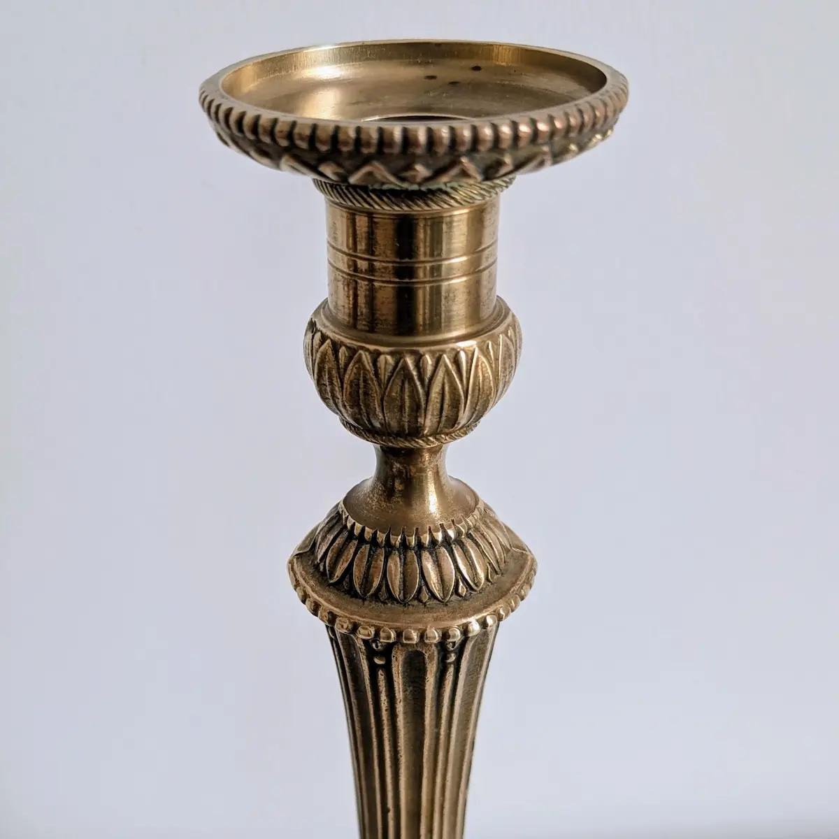 Détail du binet ciselé de perles et de feuilles d'eau sur un bougeoir en laiton de style Louis XVI.